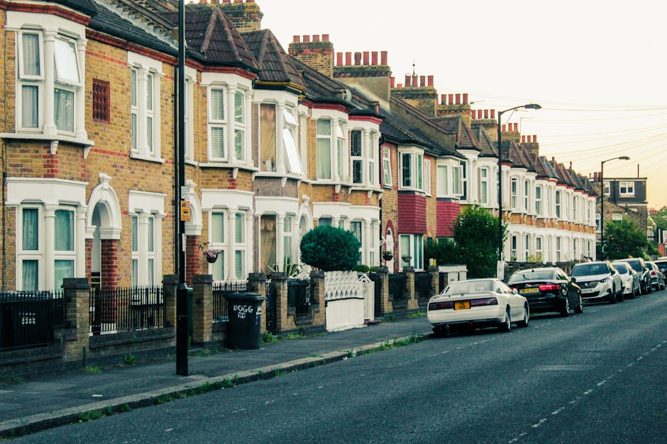 A quiet residential street during the daytime showing a road intersection with traffic calming measures including small barriers and a painted entry lane for vehicles. On the left, a 'give way' traffi